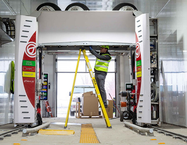 technician on a ladder installing a car wash