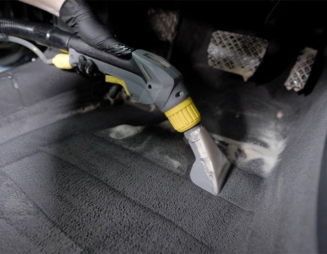 cleaning the floor of a car with a carpet scrubber
