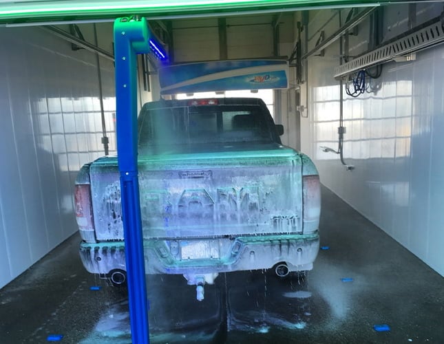 Back of a pickup truck inside a car wash covered in soap