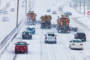 cars and snow plows on a snowy road